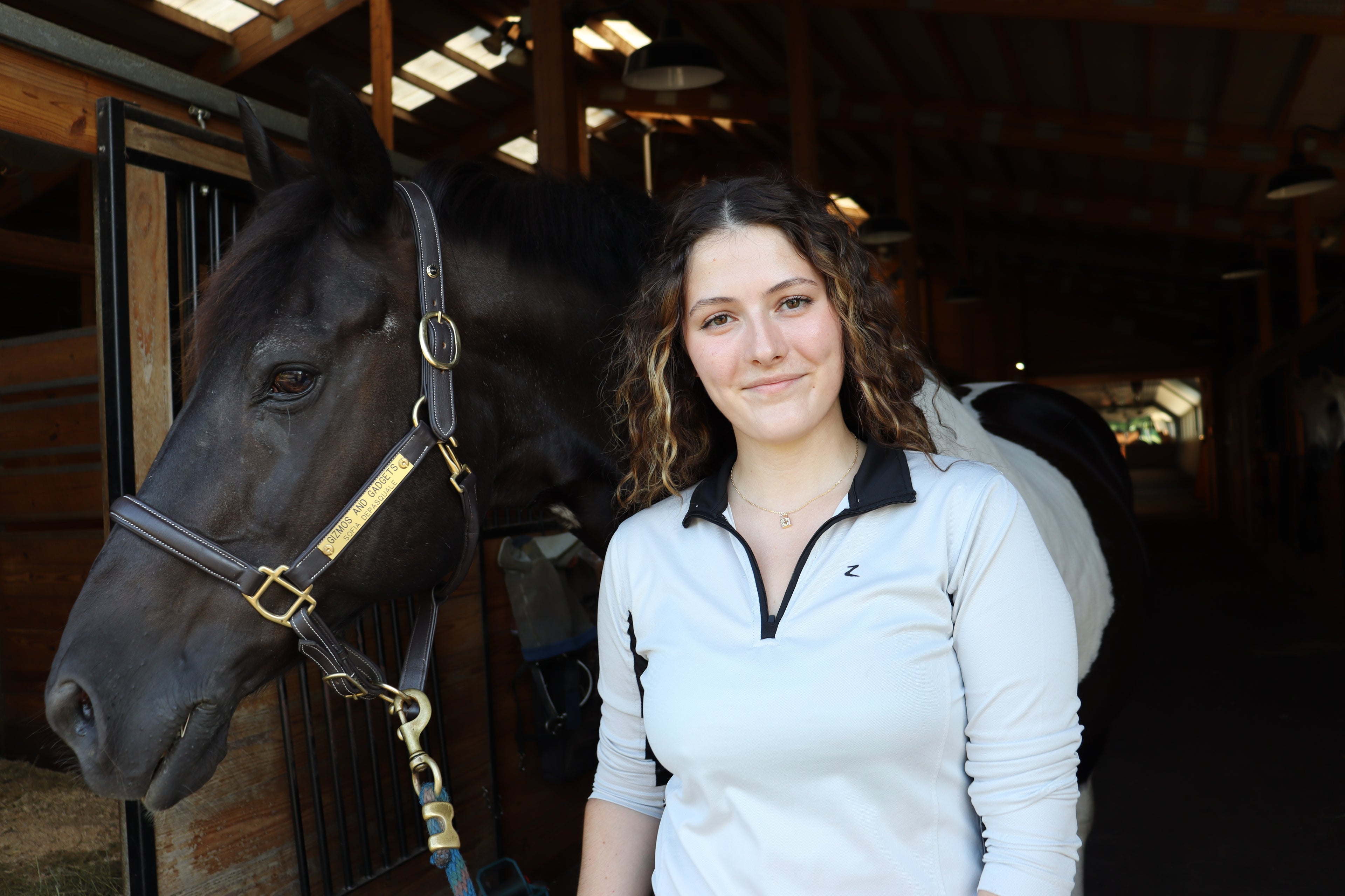 girl smiles with horse and gold lock necklace