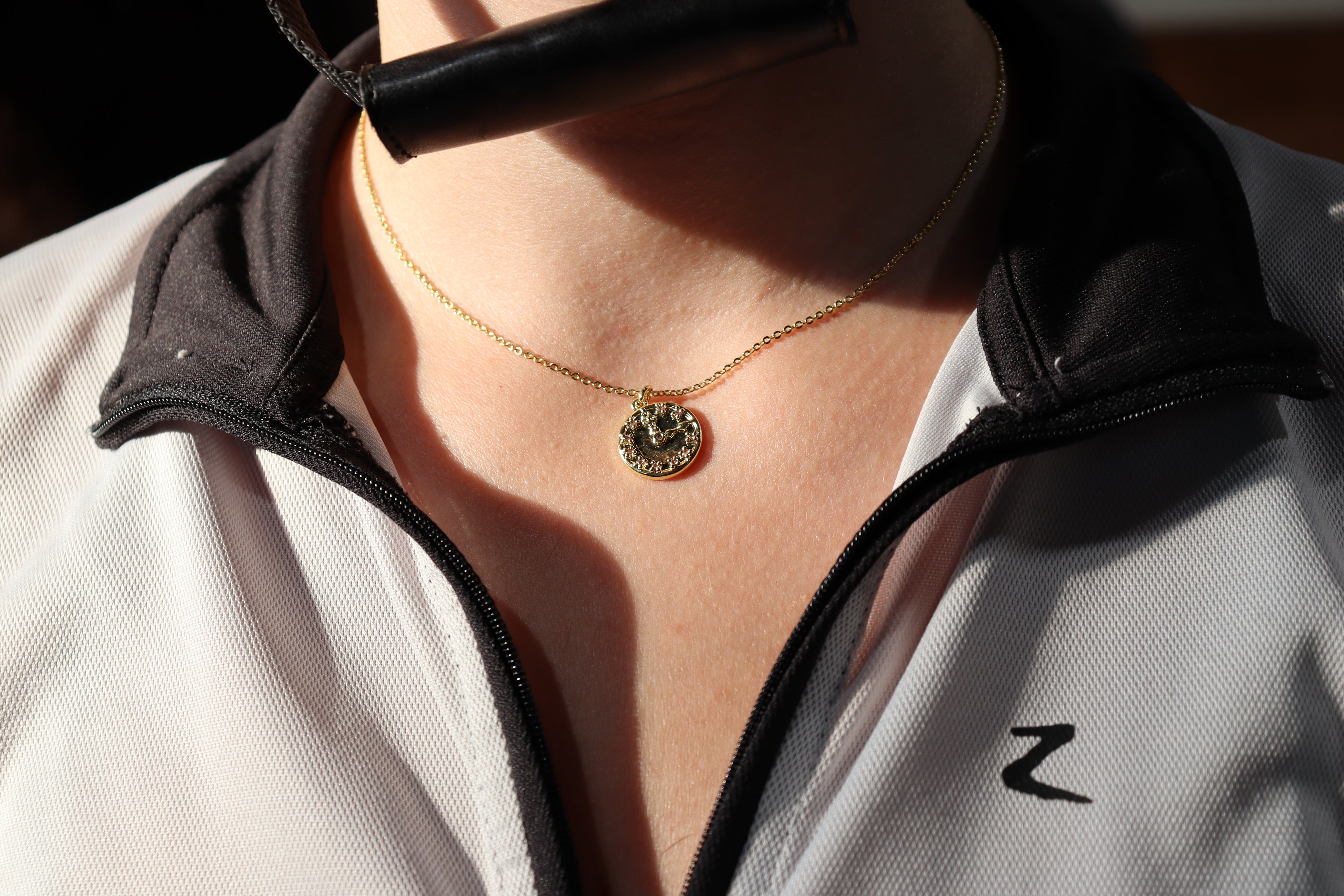 sun shining off clock necklace around girl's neck