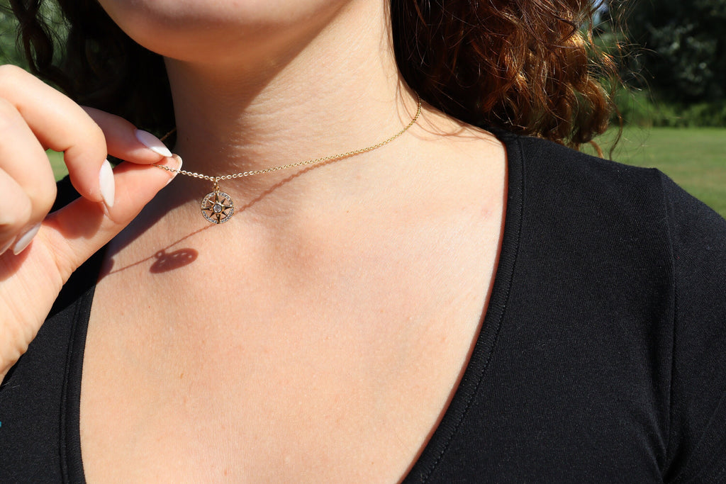 compass necklace held up on girl's neck